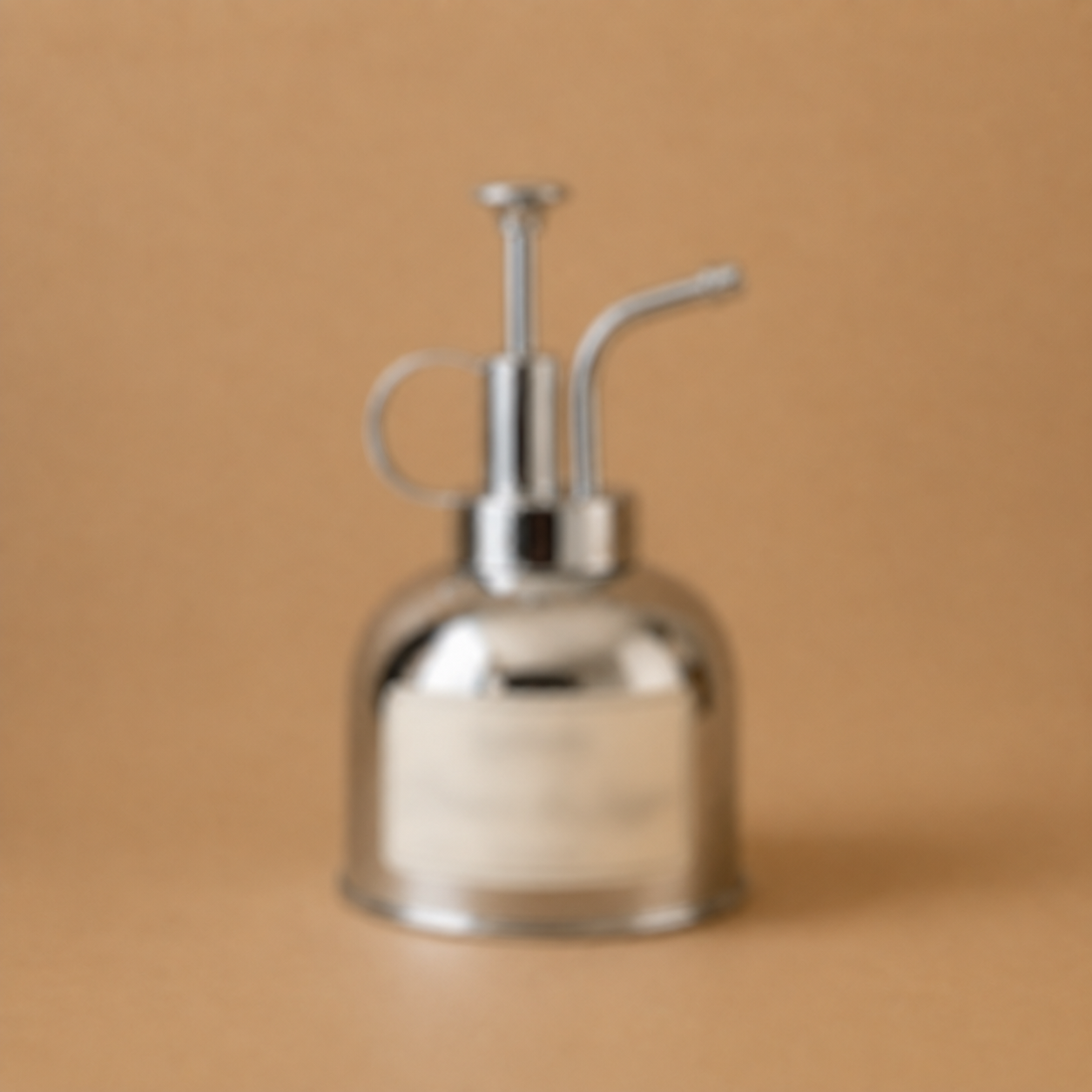 La Brume de Linge — polished metal linen mist spray bottle on a warm sand background