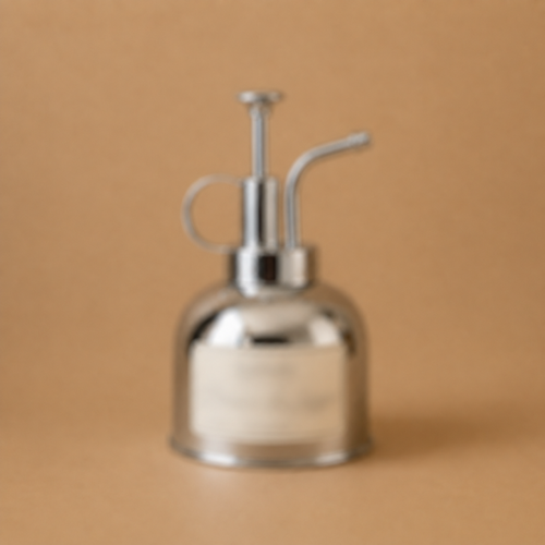 La Brume de Linge — polished metal linen mist spray bottle on a warm sand background